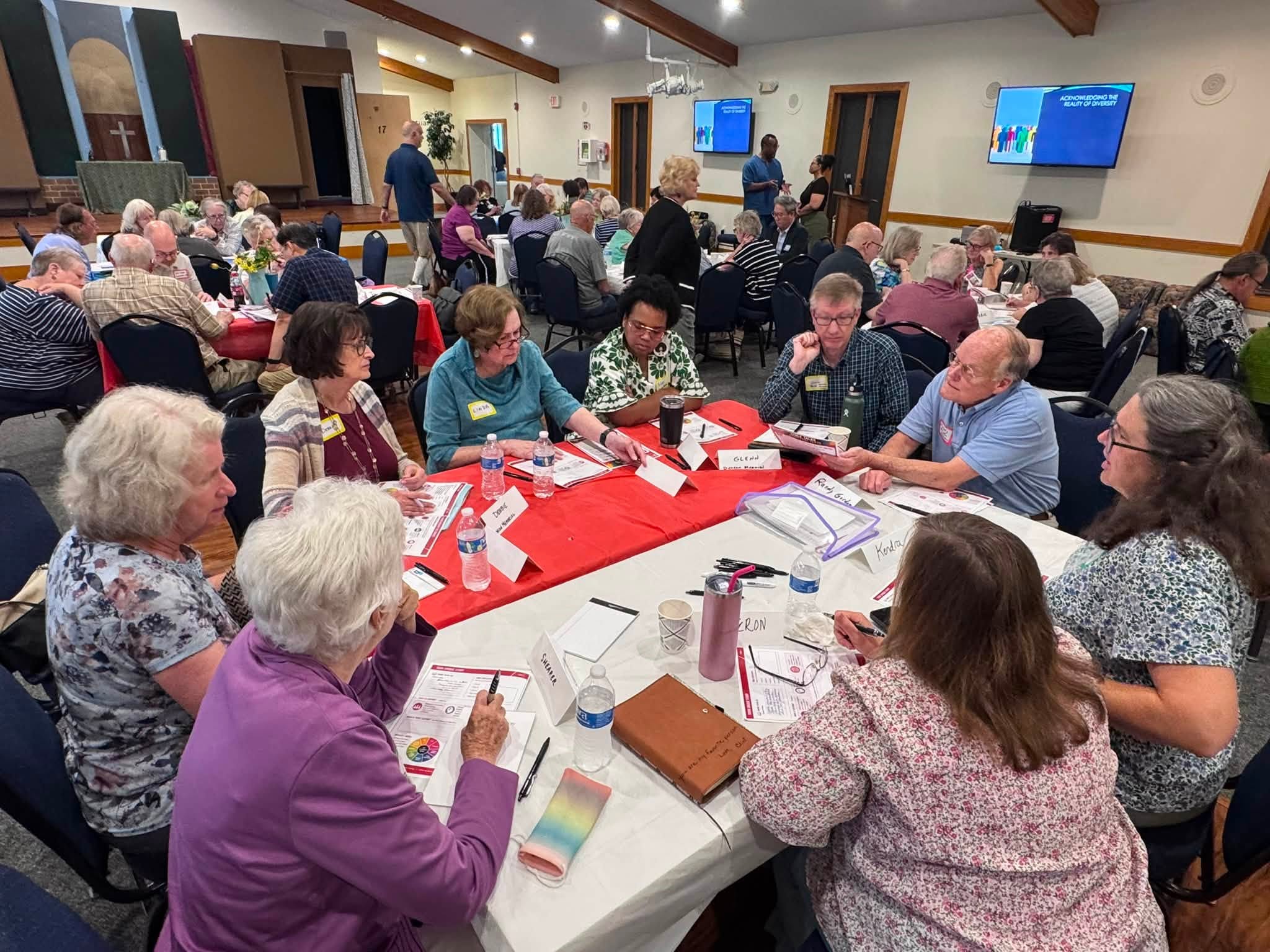 Three Notch'd District clergy and laity at tables during a training event.
